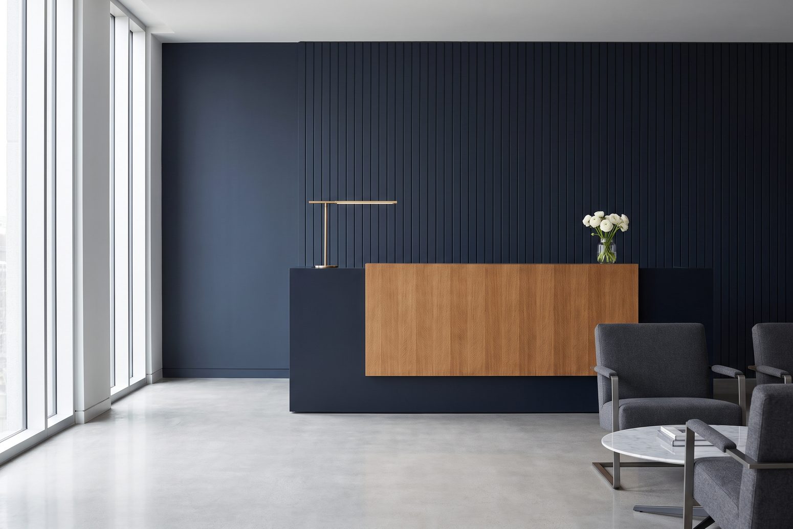 The reception area of the office, with a wood desk and a navy panelled wall.