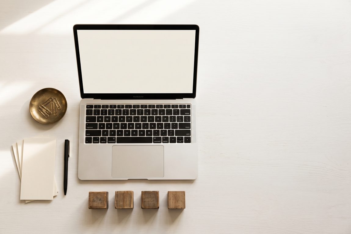 A laptop, calculator and notepad arranged on a bright desk for a planning session.